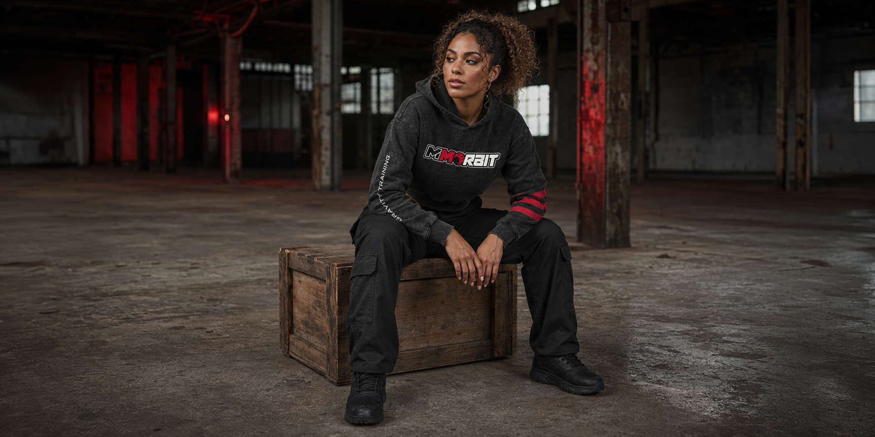 One adult woman wearing the cropped MMORBIT Gravity Training hoodie in a distinct campaign story portrait
